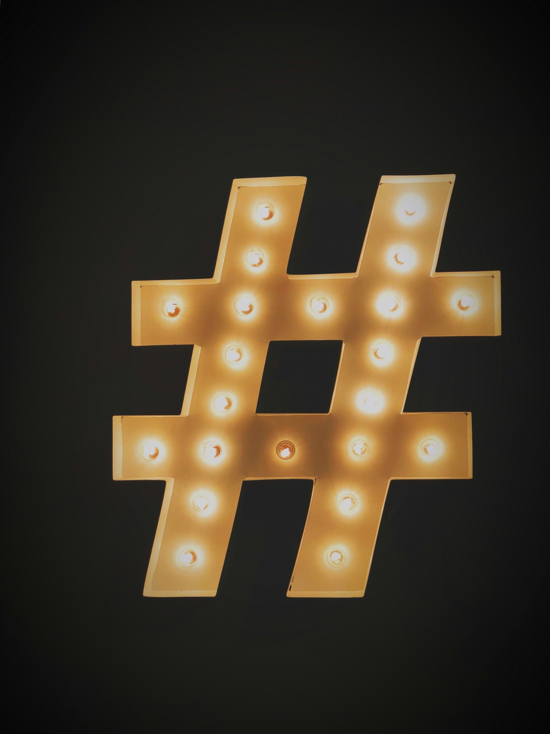 A large illuminated hashtag symbol with light bulbs shines brightly on a dark background, representing the impact of the Financial Influencer Network.