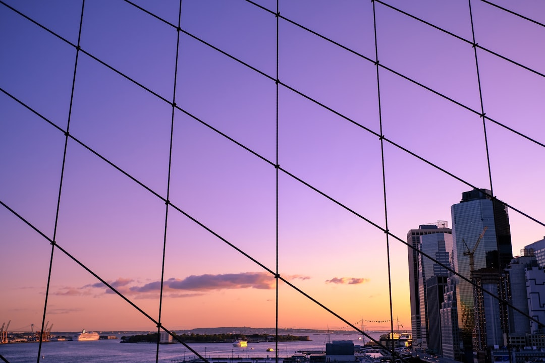 Skyline view through a lattice, where tall buildings and a harbor at sunset evoke innovative communications strategies.