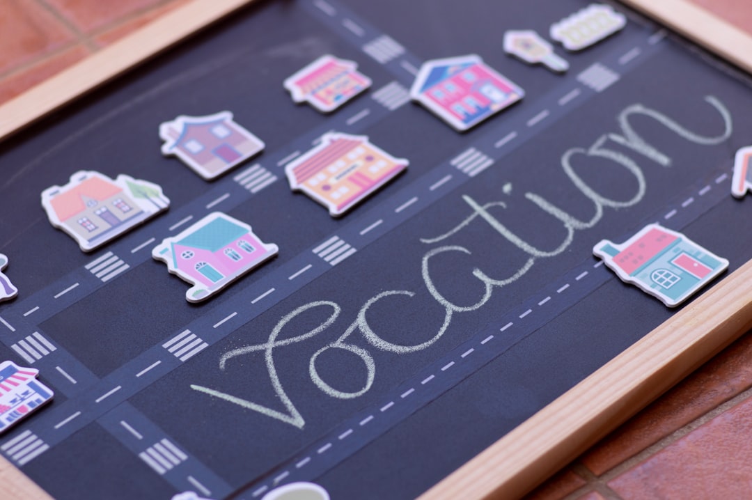 Chalkboard with "vacation" elegantly scripted in chalk, showcasing a road lined with vibrant house magnets, reminiscent of visual finance graphs illustrating life's colorful journey.