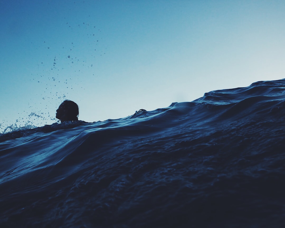 A silhouette of a person partially submerged in choppy water against a clear blue sky, with water droplets suspended mid-air, evokes the essence of data-driven content—capturing every detail in crisp clarity.