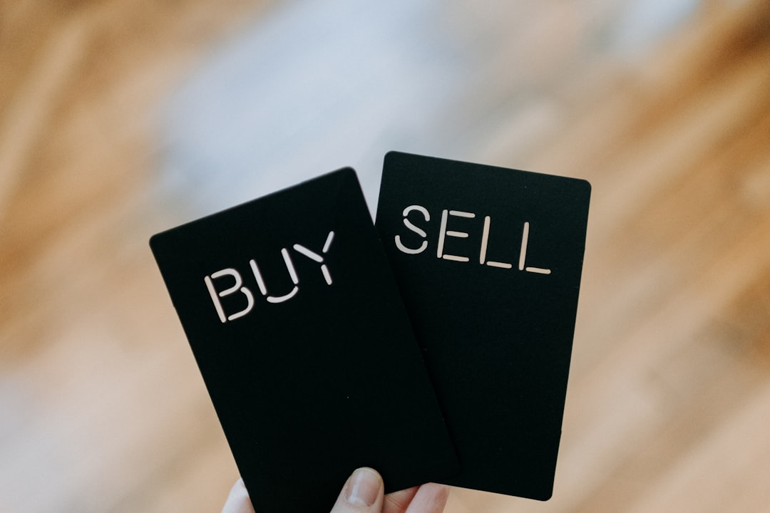 A person holds two black cards, one labeled "BUY" and the other "SELL," symbolizing key decisions in machine learning finance, set against a blurred backdrop.