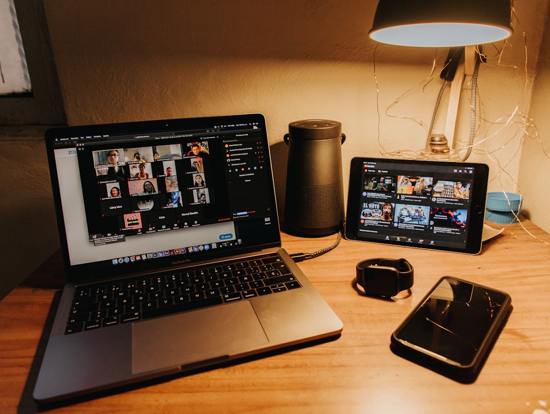 A laptop displaying a video conference, a tablet with AI financial planning tools, a smartphone, a smartwatch, a speaker, and a desk lamp are elegantly arranged on the wooden desk.