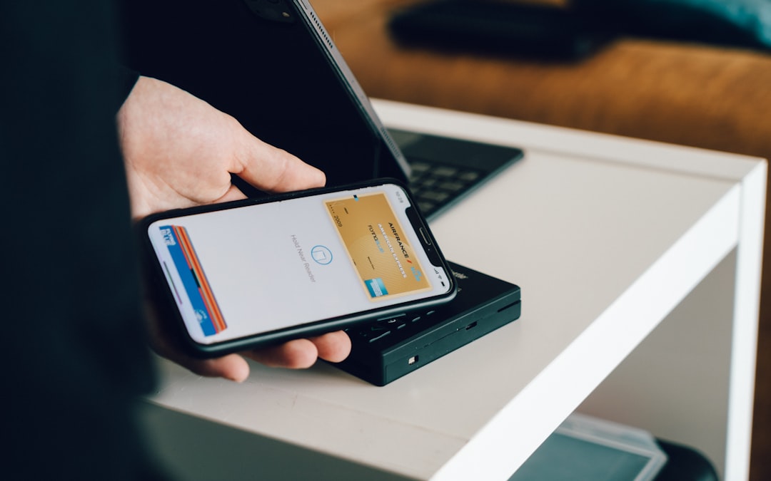 A person using a smartphone for contactless payment near a card reader on a table showcases AI-driven financial inclusion, making transactions seamless and accessible for everyone.