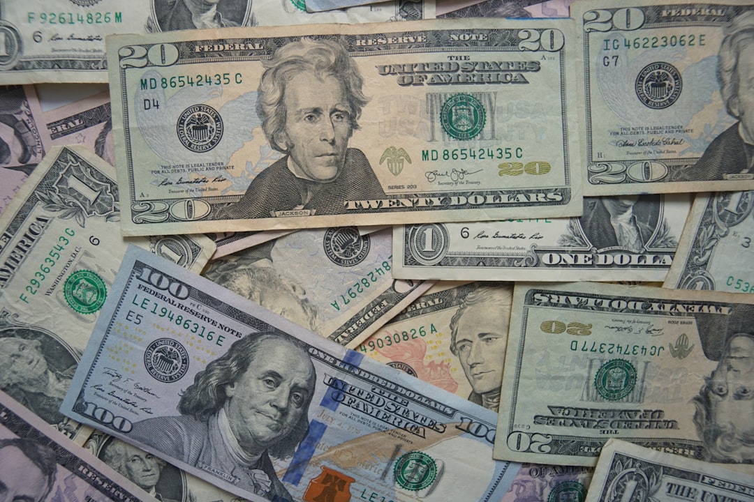 A pile of U.S. dollar bills, featuring $100, $20, and $1 notes, is scattered randomly—a snapshot reminiscent of the chaotic allure of AI investing in unpredictable markets.