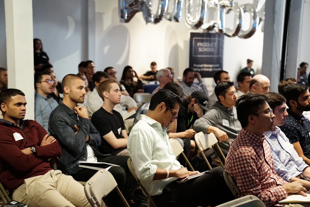 A group of people seated in rows attentively listen during an indoor event, engrossed in a presentation on financial thought leadership.