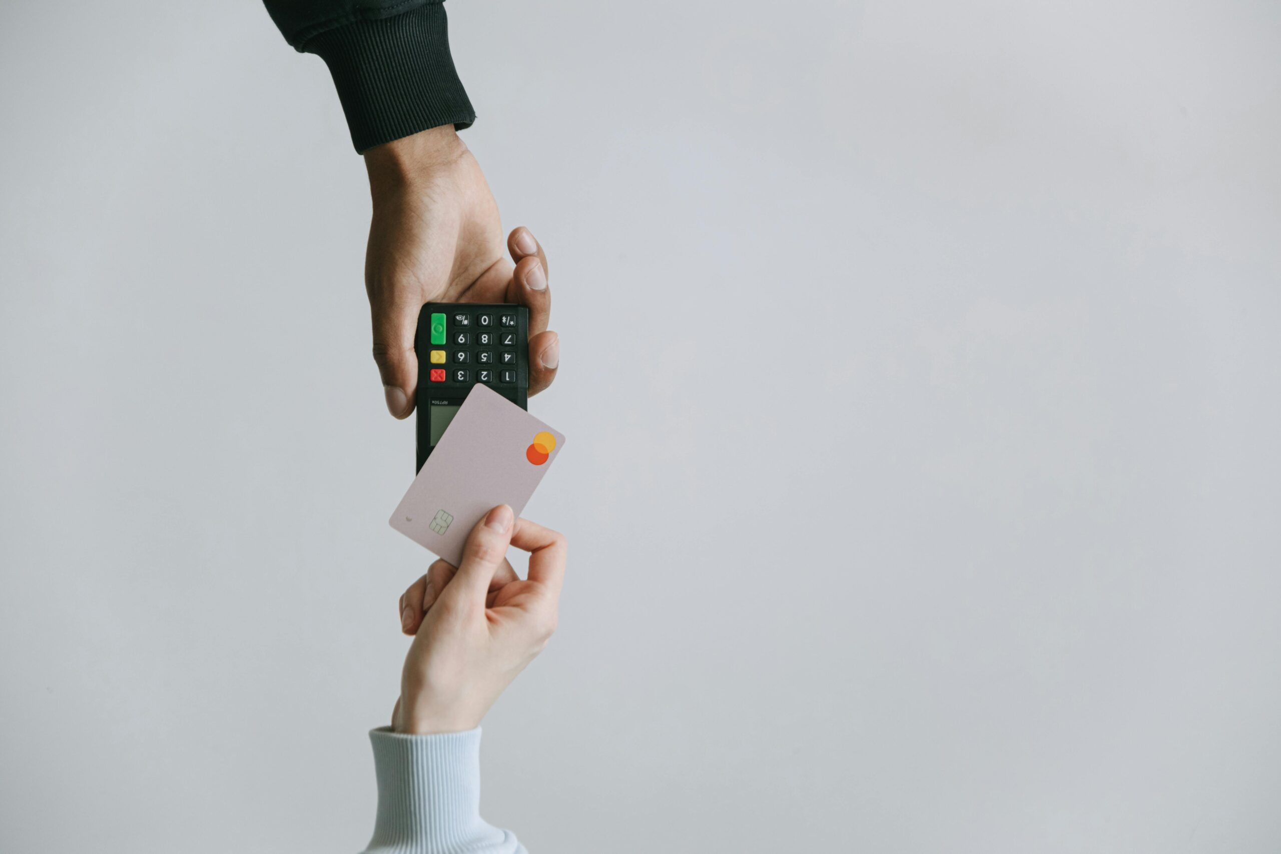 A person holds a card reader while another person taps a credit card to make a contactless payment. Employee Credit Repair